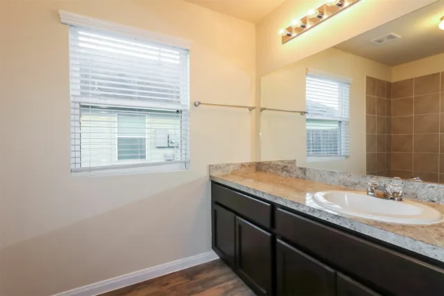 a bathroom with a granite countertop sink a vanity and a window