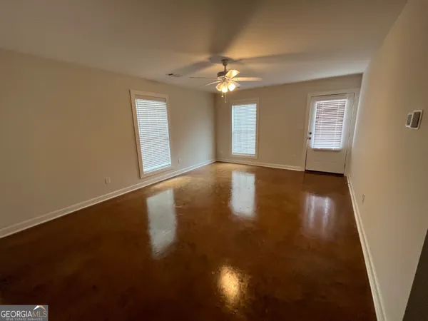 an empty room with wooden floor chandelier fan and windows
