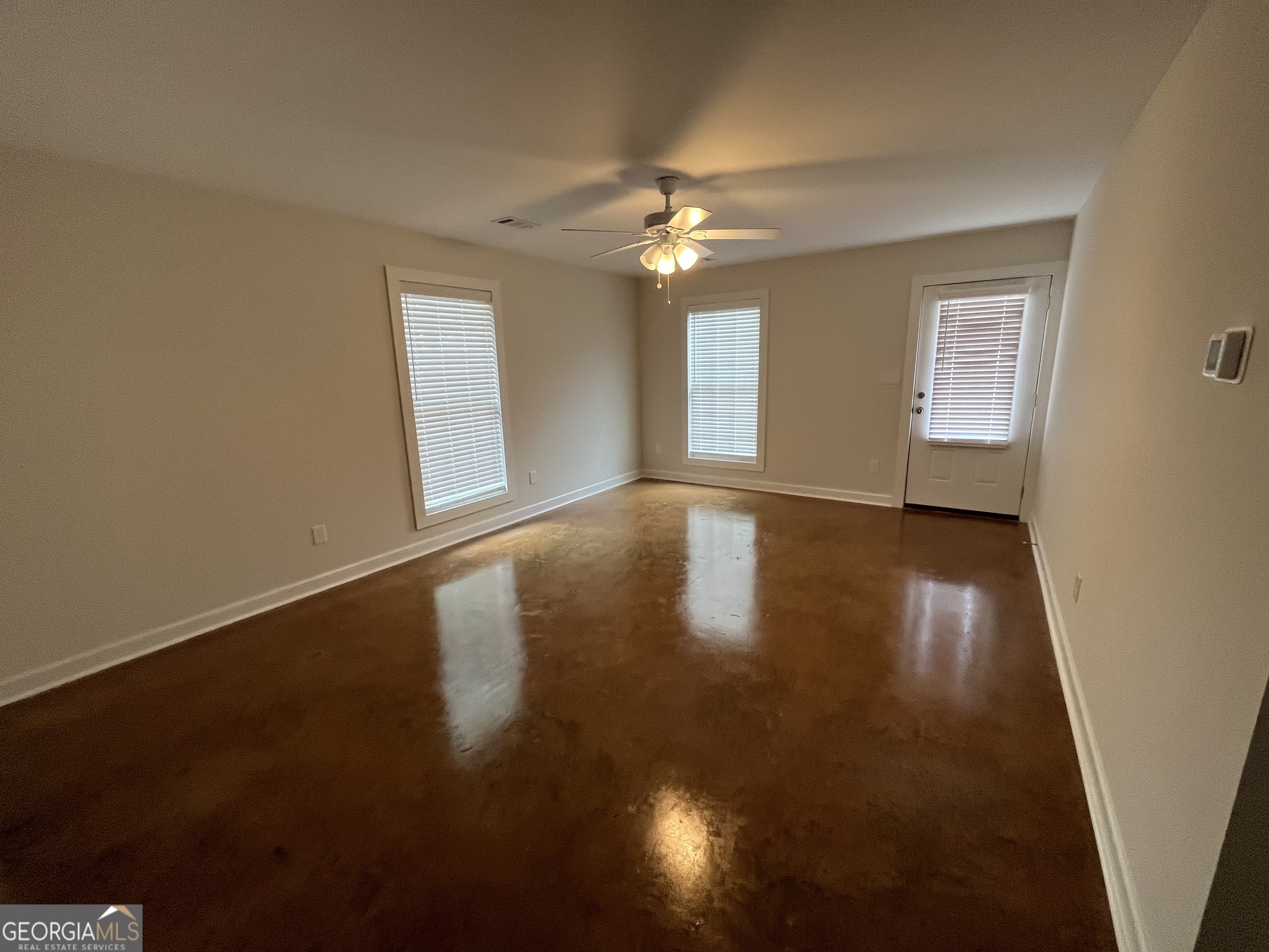 1112 3rd Street, Unit B Perry, GA 31069 - Photo 2 of 11 an empty room with wooden floor chandelier fan and windows