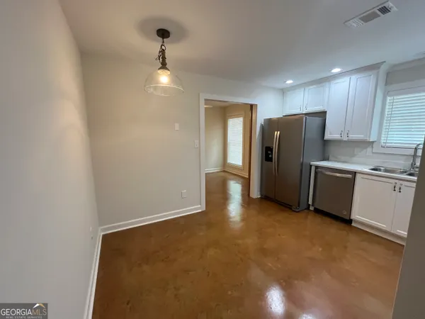 a view of a kitchen with refrigerator and wooden floor