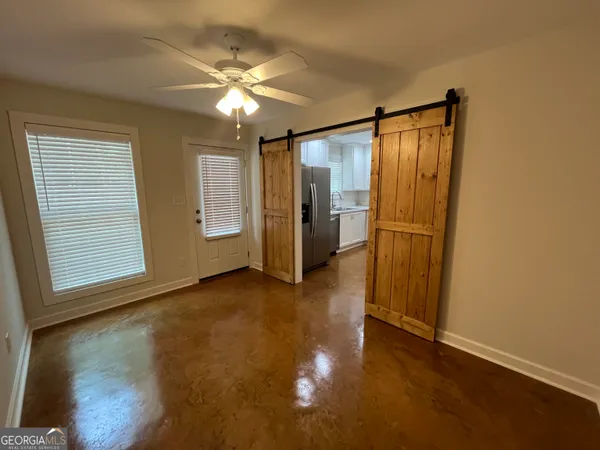 an empty room with wooden floor cabinet and windows
