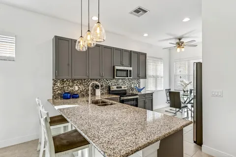 a kitchen with kitchen island granite countertop a sink refrigerator and microwave