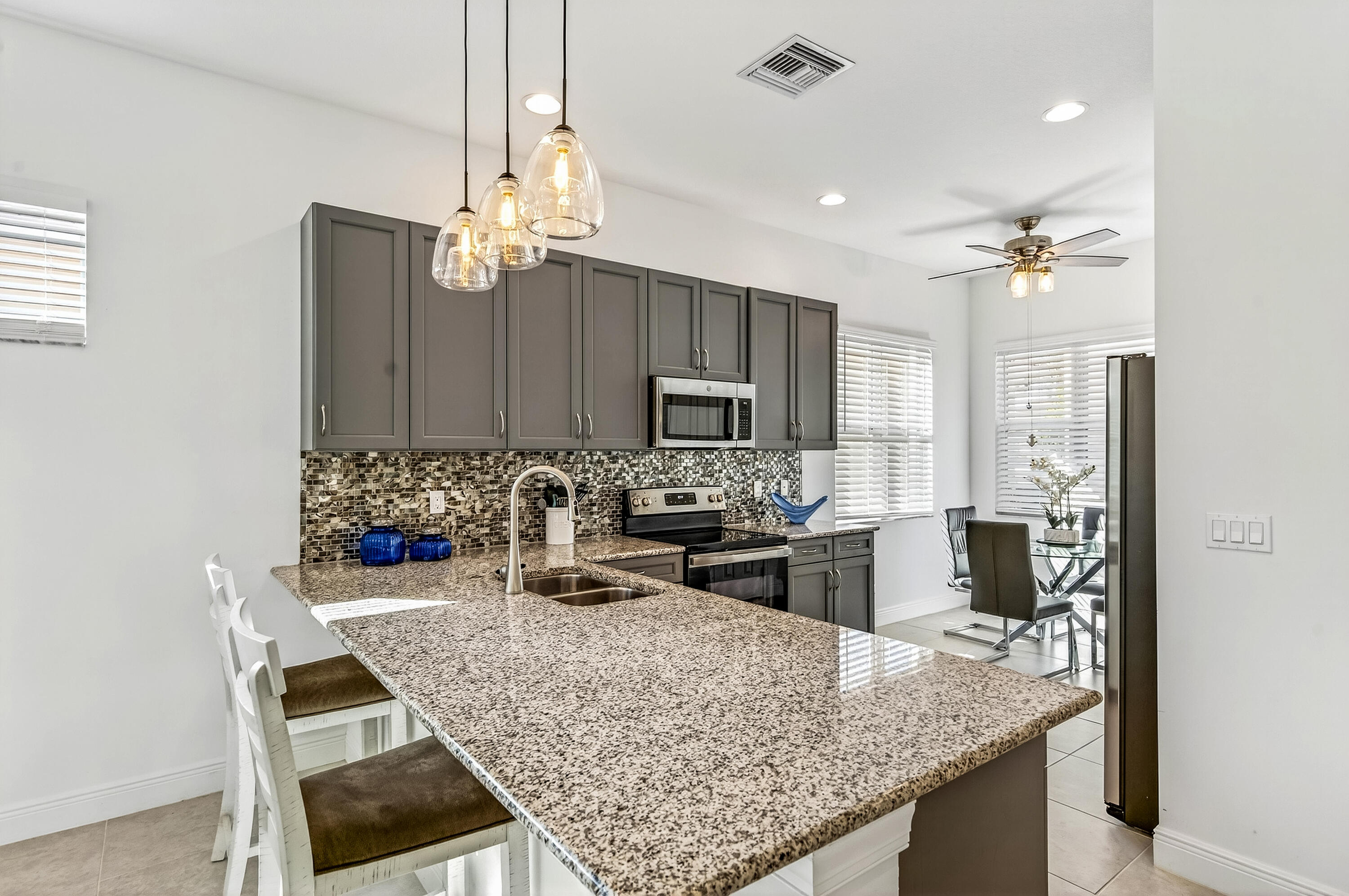 11461 Southwest Visconti Way Port St. Lucie, FL 34986 - Photo 12 of 32 a kitchen with kitchen island granite countertop a sink refrigerator and microwave