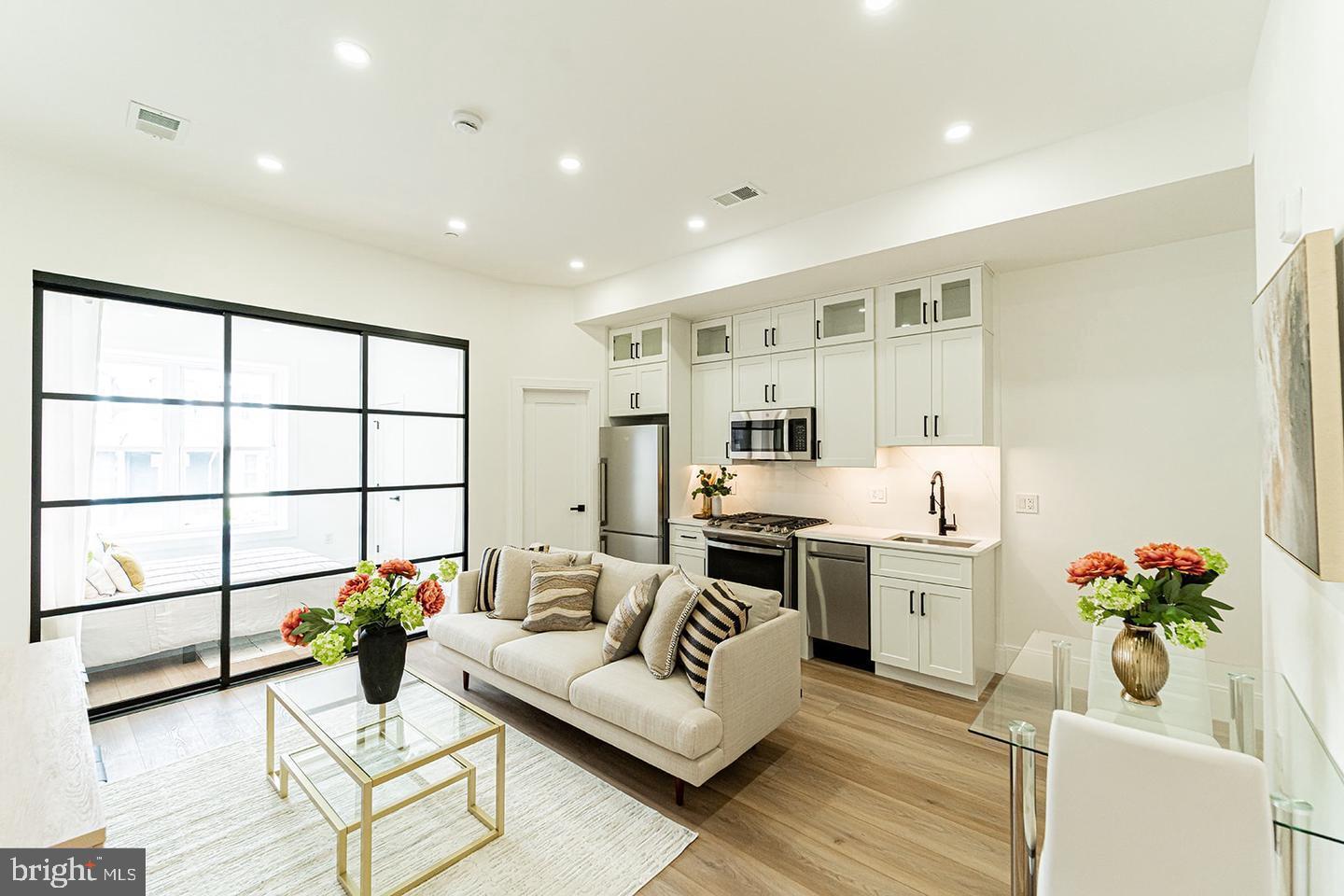 a living room with furniture kitchen and a large window
