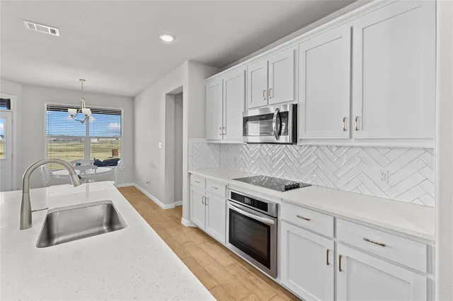a kitchen with white cabinets and appliances