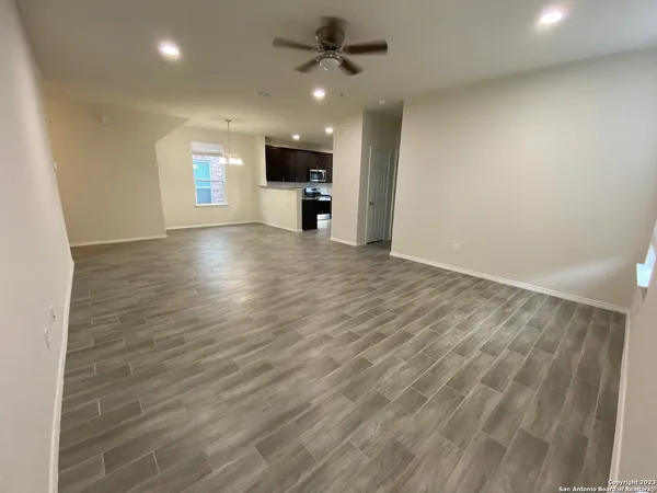 an empty room with wooden floor a ceiling fan and windows
