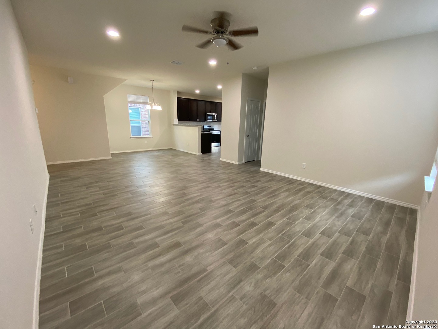 11834 Burnett Ranch San Antonio, TX 78254 - Photo 3 of 18 an empty room with wooden floor a ceiling fan and windows