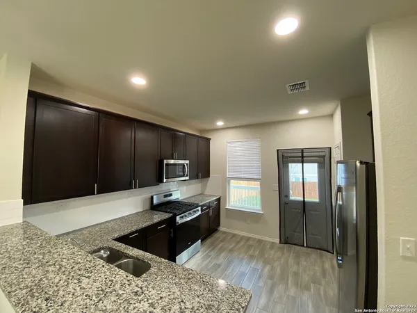 a kitchen with granite countertop a refrigerator and a stove top oven