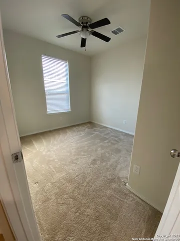 an empty room with windows and fan