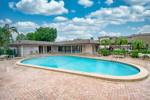 a view of pool with lawn chairs and plants