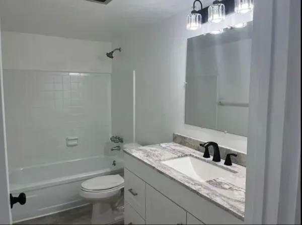 a bathroom with a granite countertop sink a toilet and shower