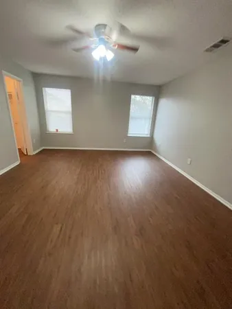 an empty room with a window and chandelier fan