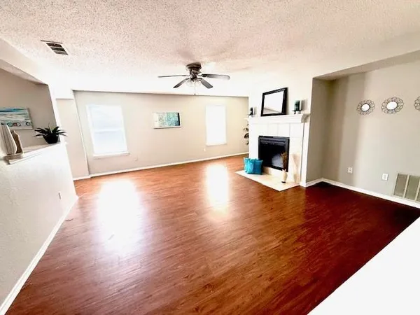 a view of a livingroom with a fireplace a ceiling fan and wooden floor