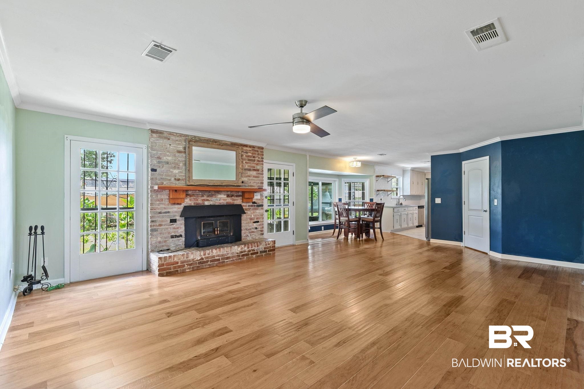 3791 Robinsonville Road Atmore, AL 36502 - Photo 12 of 55 Spacious living area featuring wood-finish flooring, a brick fireplace with wood mantel, and double French doors