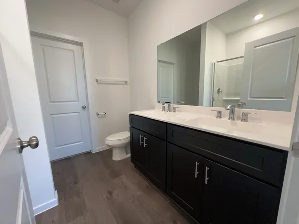 a bathroom with a double vanity sink toilet and mirror