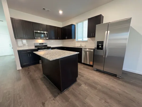 a kitchen with stainless steel appliances granite countertop a stove top oven a sink and a refrigerator