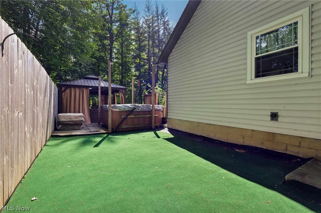 3213 Bates Road Madison, OH 44057 - Photo 34 of 45 Backyard area featuring artificial turf, wood fencing, and a built-in hot tub within a gazebo structure