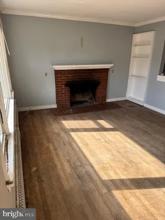 a view of empty room with wooden floor and fireplace
