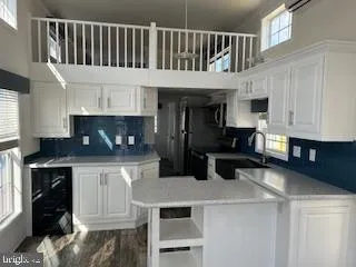 a kitchen with stainless steel appliances kitchen island granite countertop a refrigerator a stove a sink and white cabinets with wooden floor