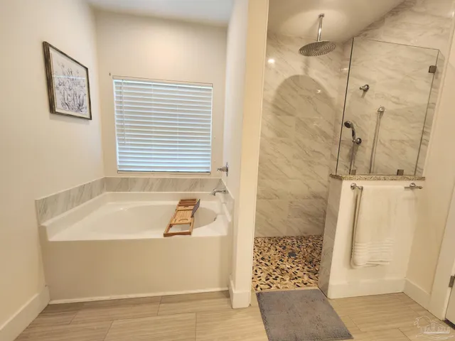 a bathroom with a tub a window and shower