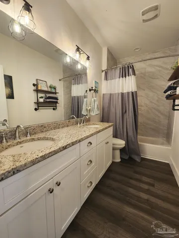 a spacious bathroom with a granite countertop sink a toilet a mirror and shower