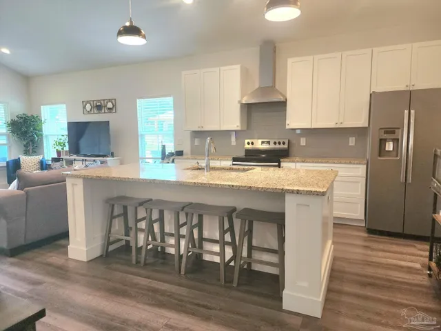 a kitchen with a table chairs a sink dishwasher a refrigerator and cabinets with wooden floor