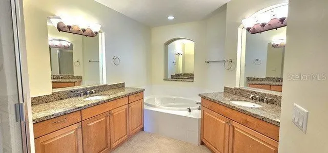a bathroom with a granite countertop sink mirror and a bathtub