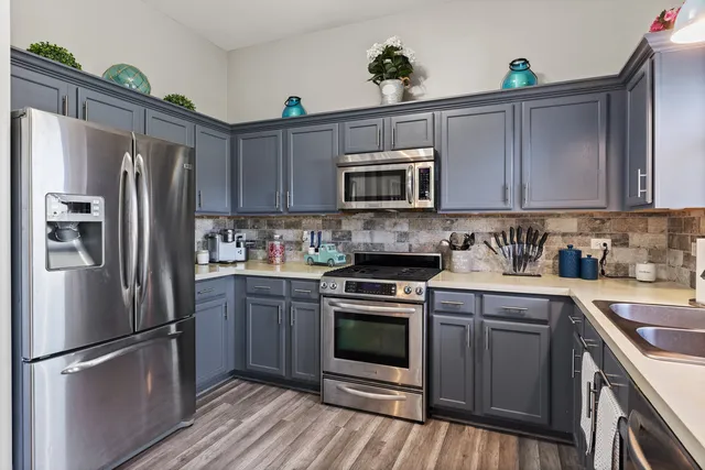 a kitchen with stainless steel appliances granite countertop a refrigerator stove a sink and dishwasher with wooden floor