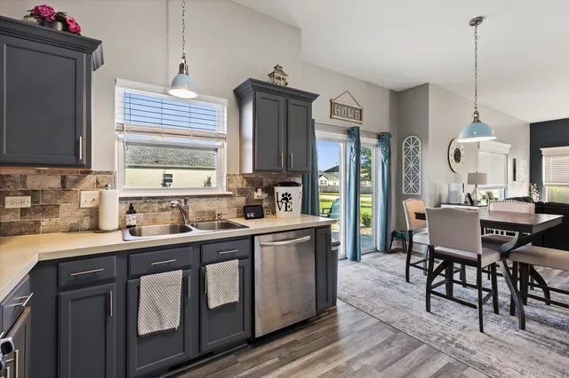 a kitchen with stainless steel appliances granite countertop a sink a stove a refrigerator cabinets and a dining table