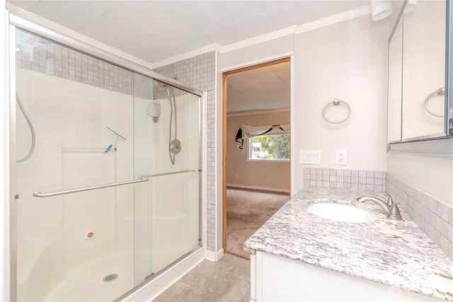 a bathroom with a granite countertop sink a mirror and shower