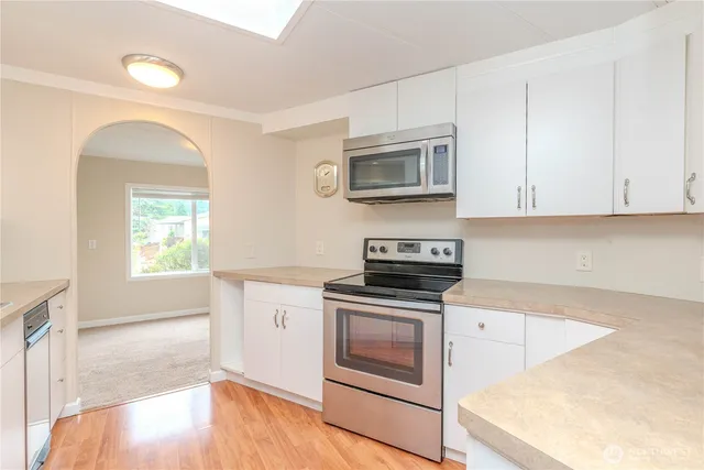 a kitchen with stainless steel appliances granite countertop a stove a microwave and white cabinets