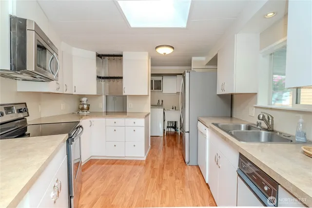 a kitchen that has a lot of cabinets in it wooden floors and stainless steel appliances