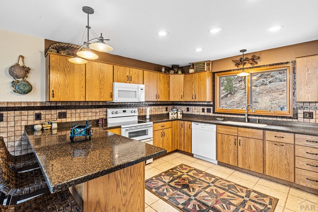 1301 Pheasant Loop Westcliffe, CO 81252 - Photo 9 of 27 a kitchen with stainless steel appliances granite countertop wooden cabinets a stove a sink and a microwave