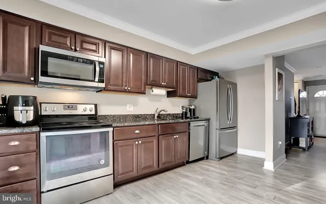 a kitchen with stainless steel appliances granite countertop a stove top oven a sink dishwasher a refrigerator and cabinets with wooden floor