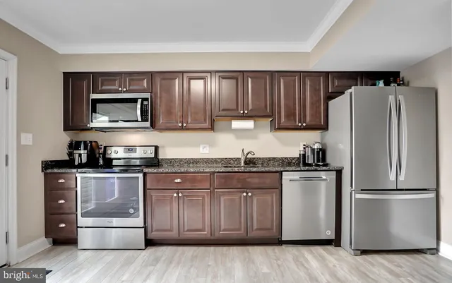 a kitchen with stainless steel appliances granite countertop a refrigerator stove and sink with wooden cabinets