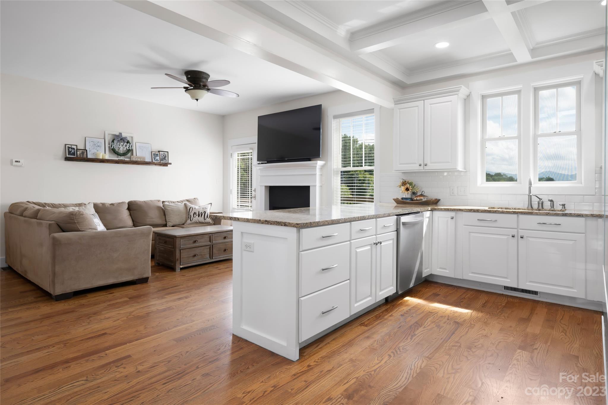 1480 Jenkins Valley Road Alexander, NC 28701 - Photo 15 of 40 a large white open kitchen with stainless steel appliances granite countertop a stove a sink dishwasher a microwave oven and a dining table with wooden floor