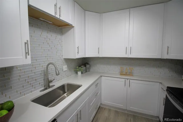 a kitchen with stainless steel appliances granite countertop a sink a stove and white cabinets