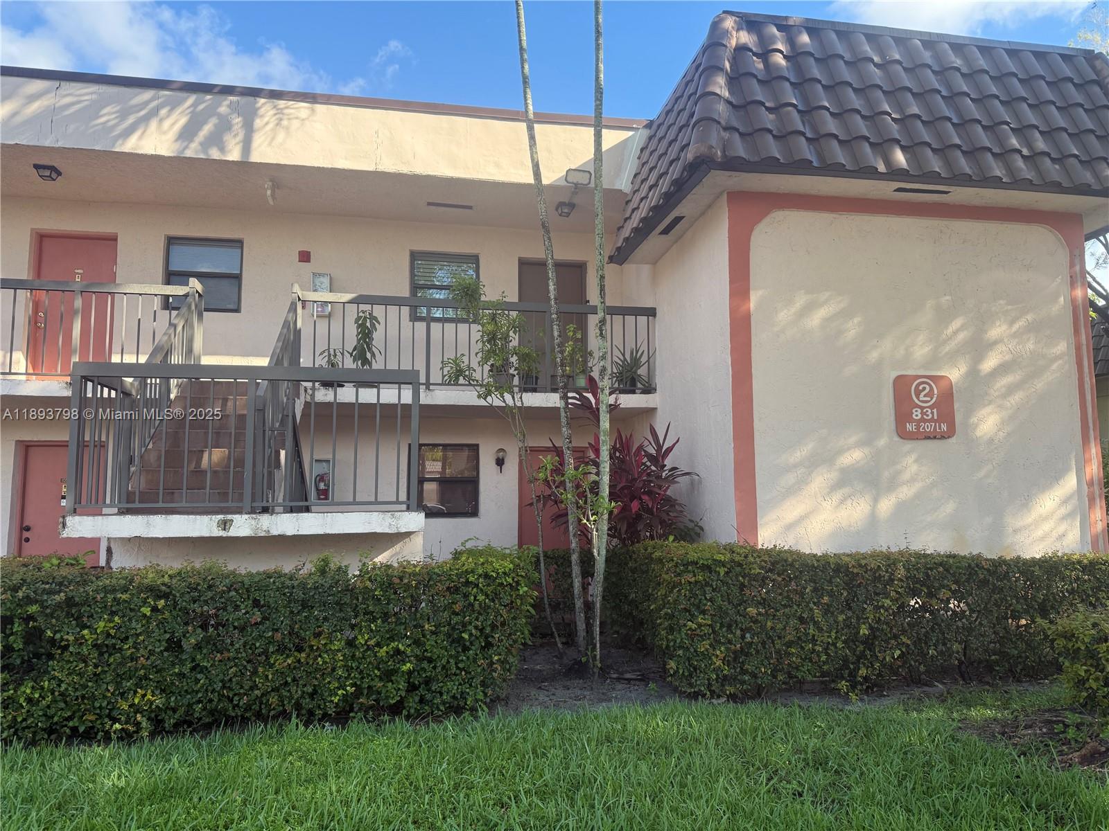 831 Northeast 207th Lane, Unit 2106 Miami, FL 33179 - Photo 3 of 13 a view of a house with a small yard and a wooden fence