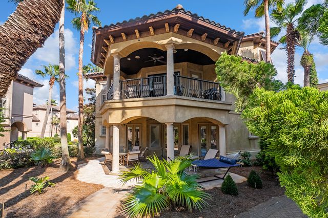 a view of a white house with large windows and couches chairs