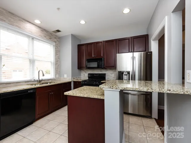 a kitchen with stainless steel appliances granite countertop a sink stove refrigerator and cabinets