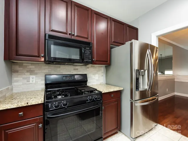 a kitchen with granite countertop a refrigerator stove and microwave