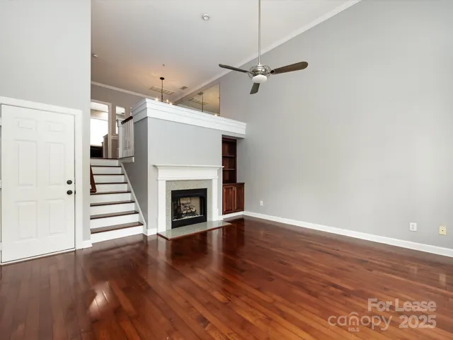 an empty room with wooden floor a fireplace a ceiling fan and wooden floor