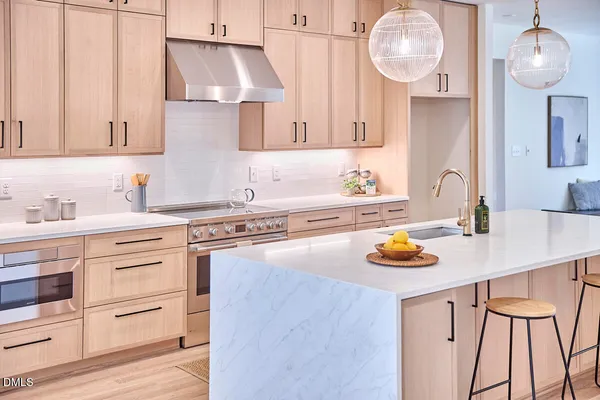 a large kitchen with kitchen island a large counter space a large window and stainless steel appliances