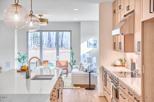 a kitchen with stainless steel appliances granite countertop a sink a stove a refrigerator and island with wooden floor