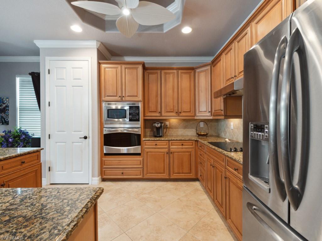 9522 Piacere Way Naples, FL 34113 - Photo 11 of 48 Kitchen featuring ornamental molding, ceiling fan, under cabinet range hood, backsplash, and stainless steel appliances