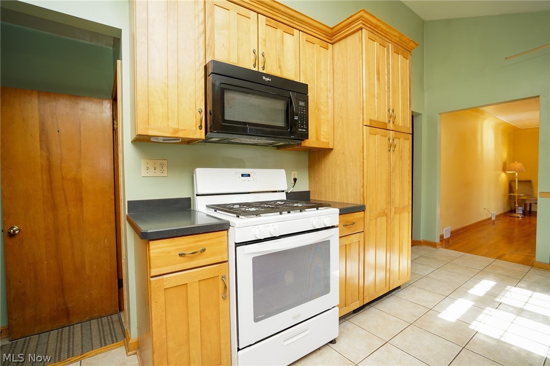 453 Omar Street Struthers, OH 44471 - Photo 16 of 27 Kitchen featuring white gas range oven, black microwave, dark countertops, and light wood finish cabinets