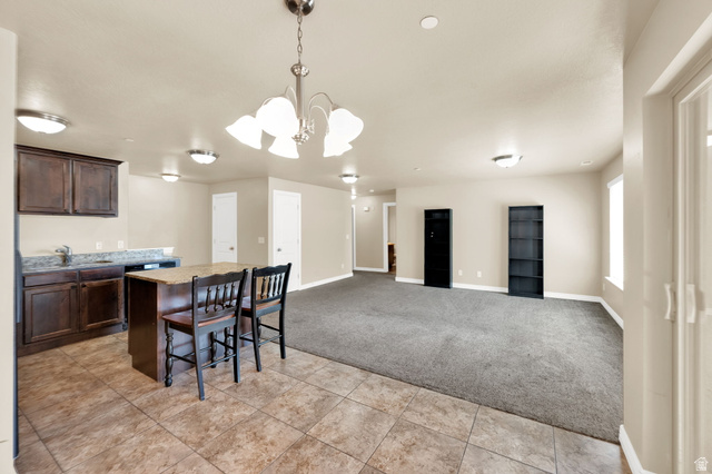 909 South Main Street, Unit G Layton, UT 84041 - Photo 9 of 25 Spacious main living area featuring a kitchen island with seating, dark wood cabinetry, and a tile backsplash