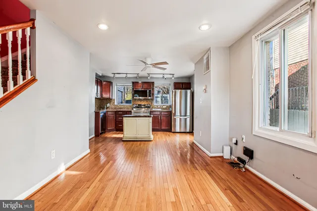 a kitchen with stainless steel appliances granite countertop a stove top oven a sink and white cabinets with wooden floor