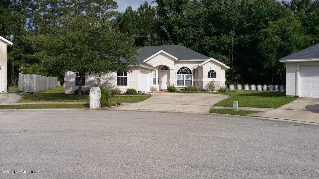 a view of a house with a yard and large trees