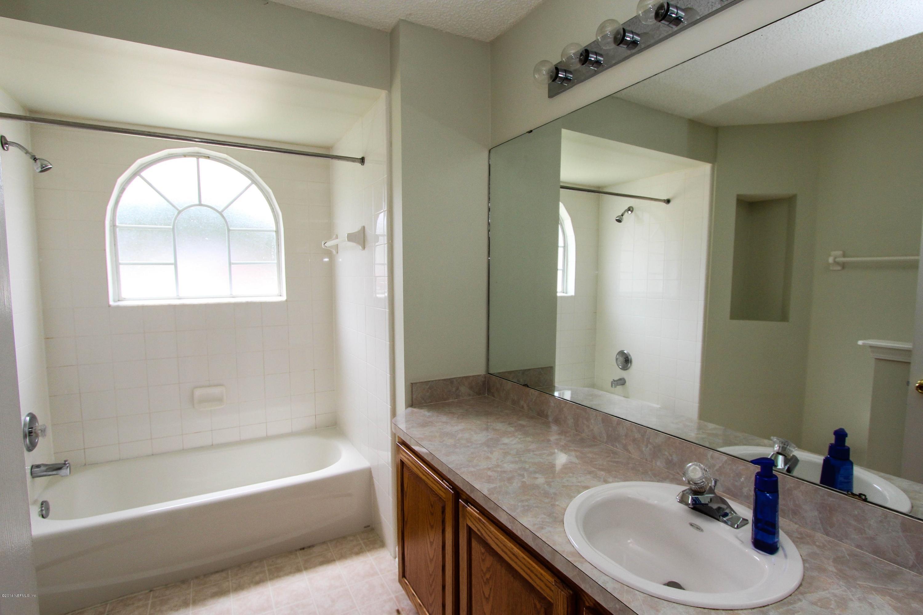 2750 Archer Street Middleburg, FL 32068 - Photo 24 of 34 a bathroom with a granite countertop sink a mirror and a bathtub